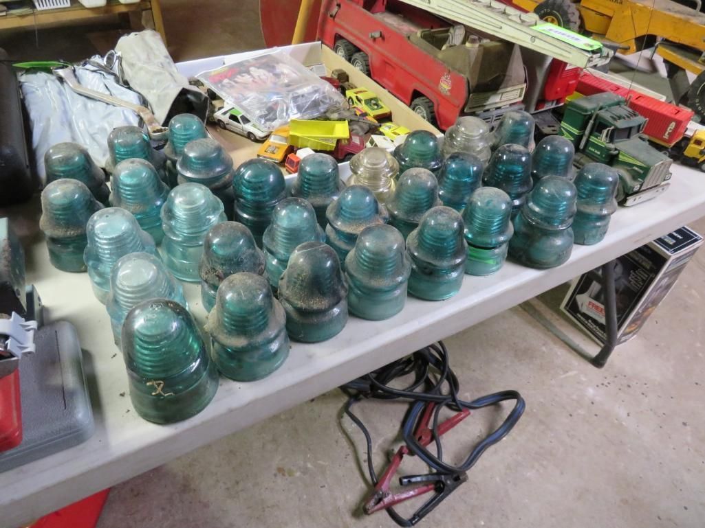 Row of teal glass insulators on a table, with other items in the background.