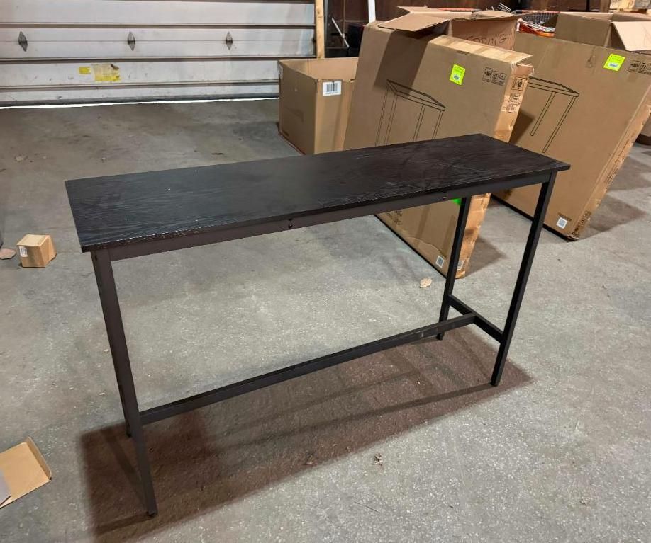 Black topped metal desk in a workshop setting with cardboard boxes.