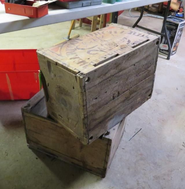 Two weathered wooden crates stacked on the floor. One has a printed design on its top.