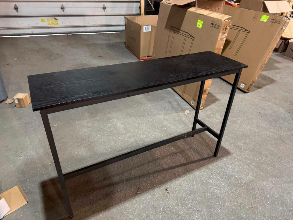 Black metal console table with a textured top in a warehouse setting.