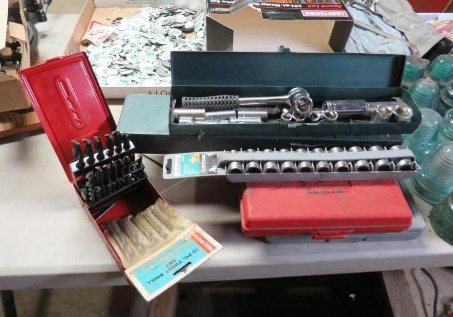 Various toolboxes open, containing sockets, bits, and a ratchet, displayed on a table.