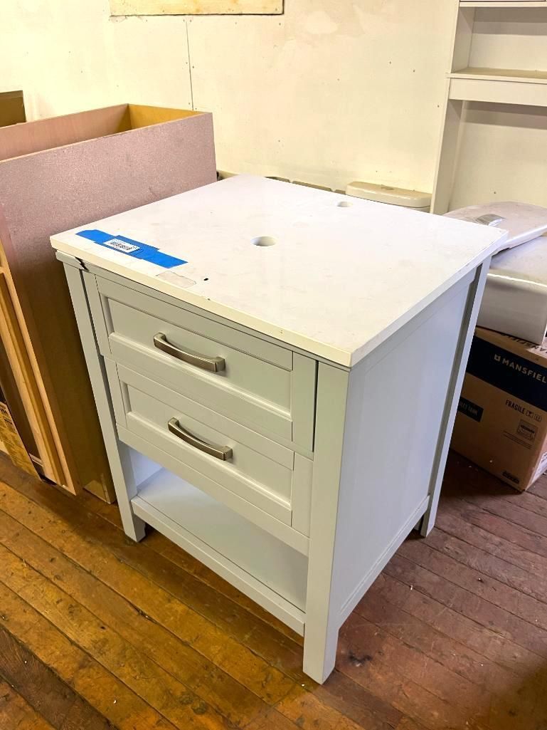 White bathroom vanity with drawers and open shelf on a wood floor.