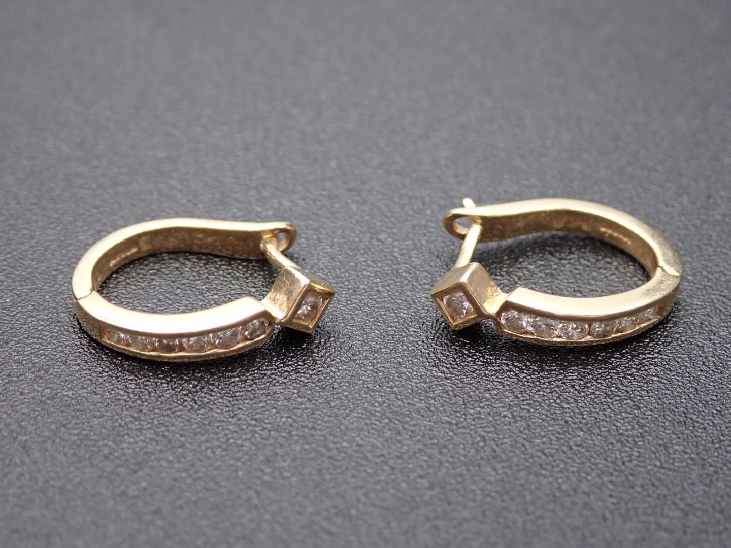 Gold hoop earrings with embedded square-cut gemstones.