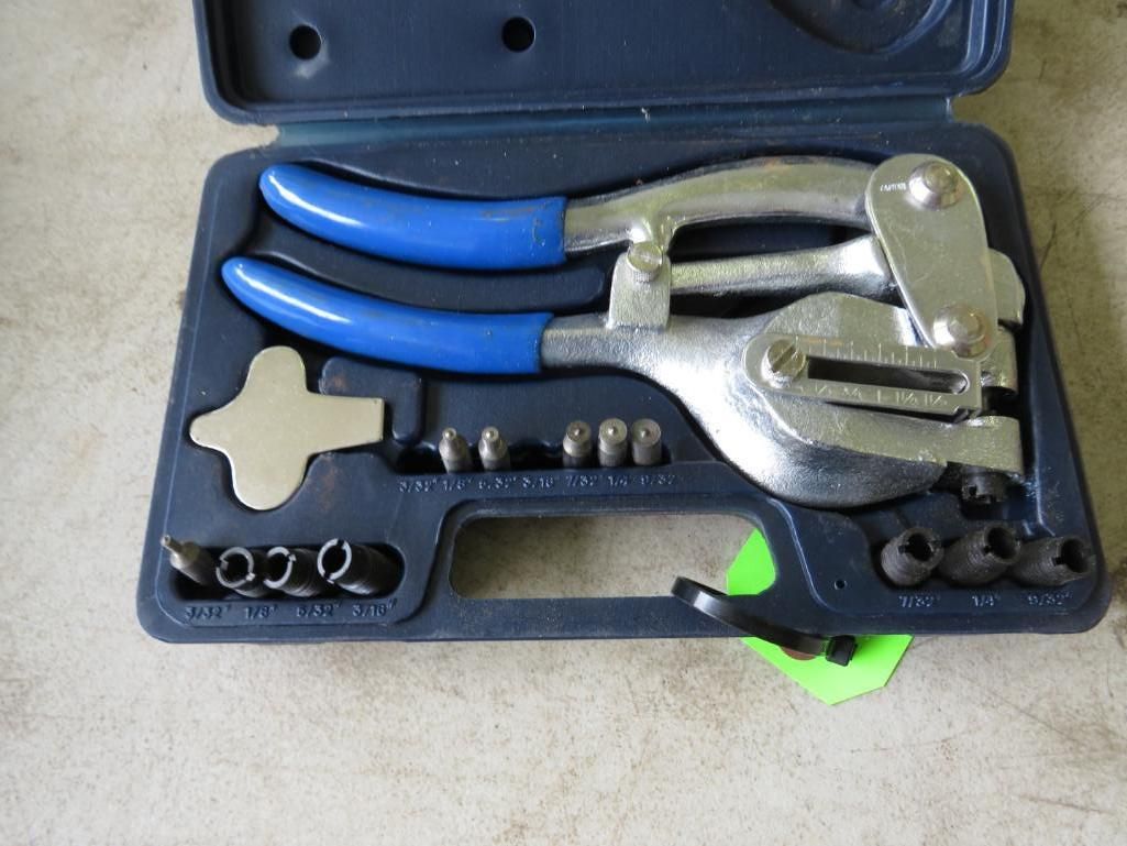A blue case holding a silver rivet tool with blue handles and rivets.
