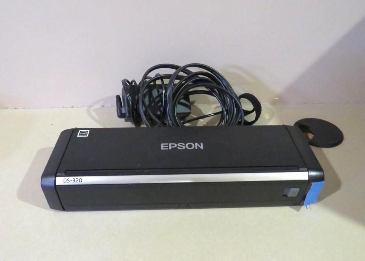 Epson ES-220 scanner on a table with a black power cord and a small, black disk.