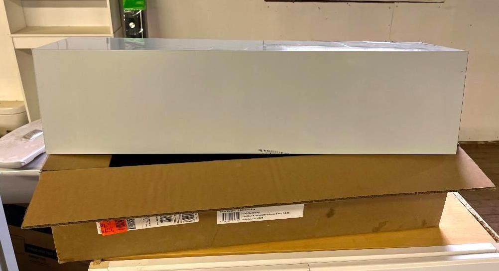 White cabinet on top of a cardboard box in a room.