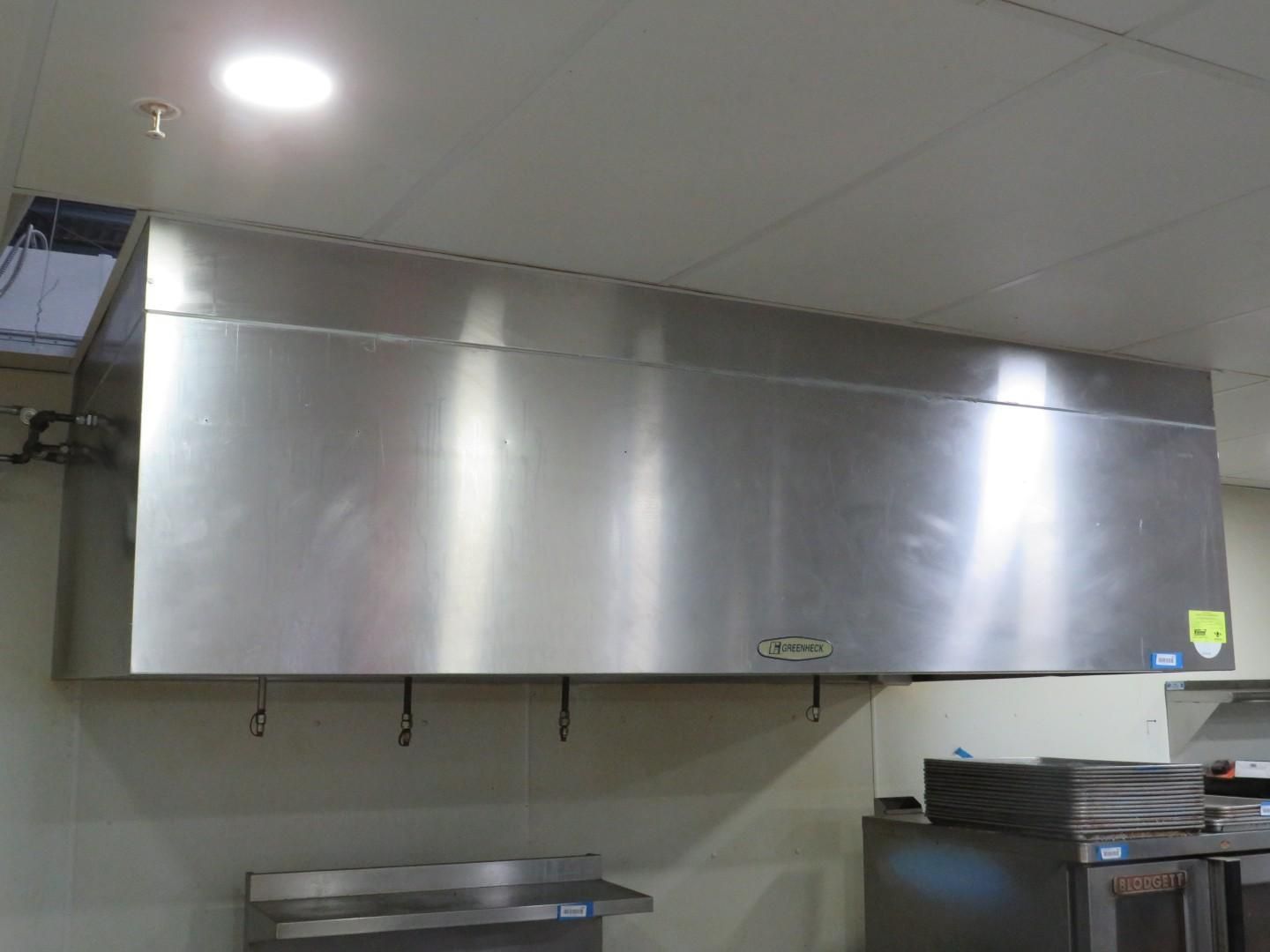 Stainless steel commercial kitchen exhaust hood mounted on wall.