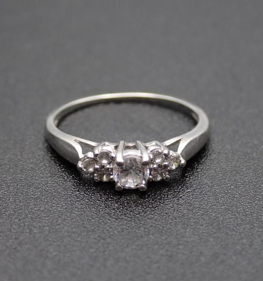 Silver ring with a central square gemstone and flanking smaller stones.