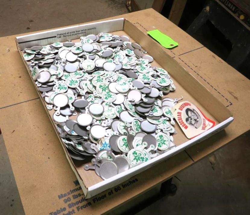 Tray filled with numerous small, round, white and gray objects with adhesive backing, likely buttons.