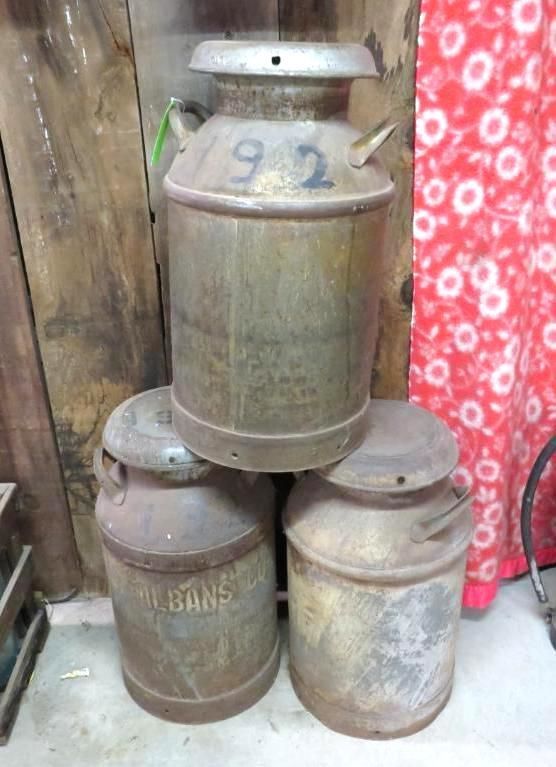Three metal milk cans stacked; one on top has the number 192.