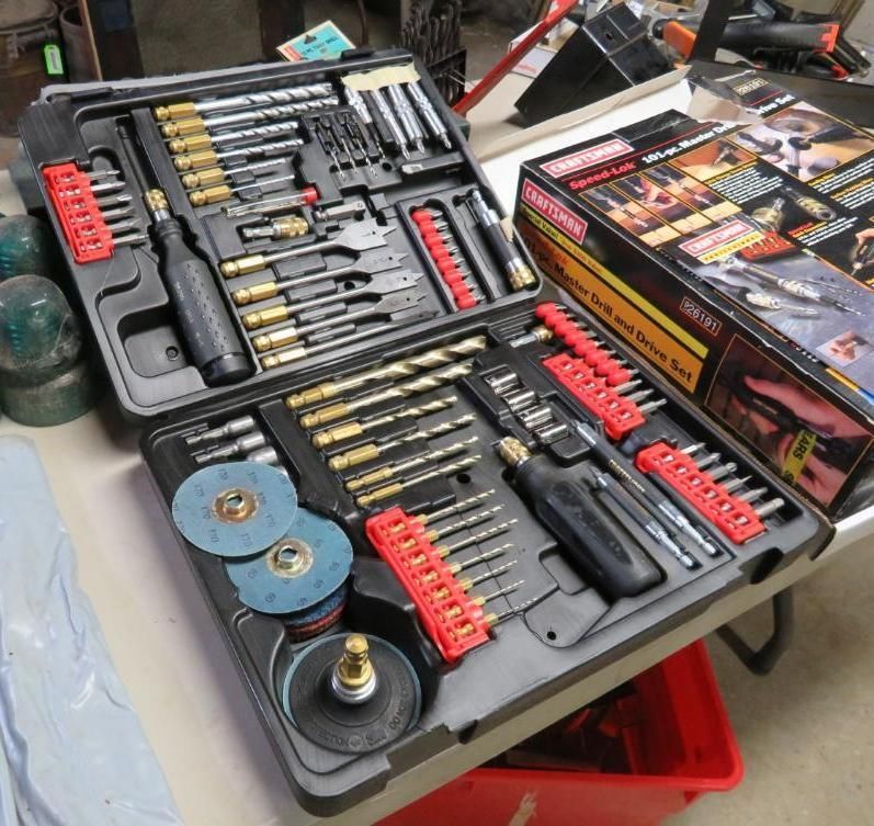 Open toolbox filled with drill bits, screwdriver bits, and other tools, next to a box.
