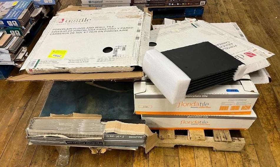 Various cardboard boxes and a black electronic device are stacked on pallets.