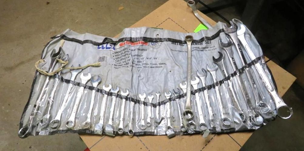 Set of wrenches in a roll-up tool bag, lying on a cardboard surface.
