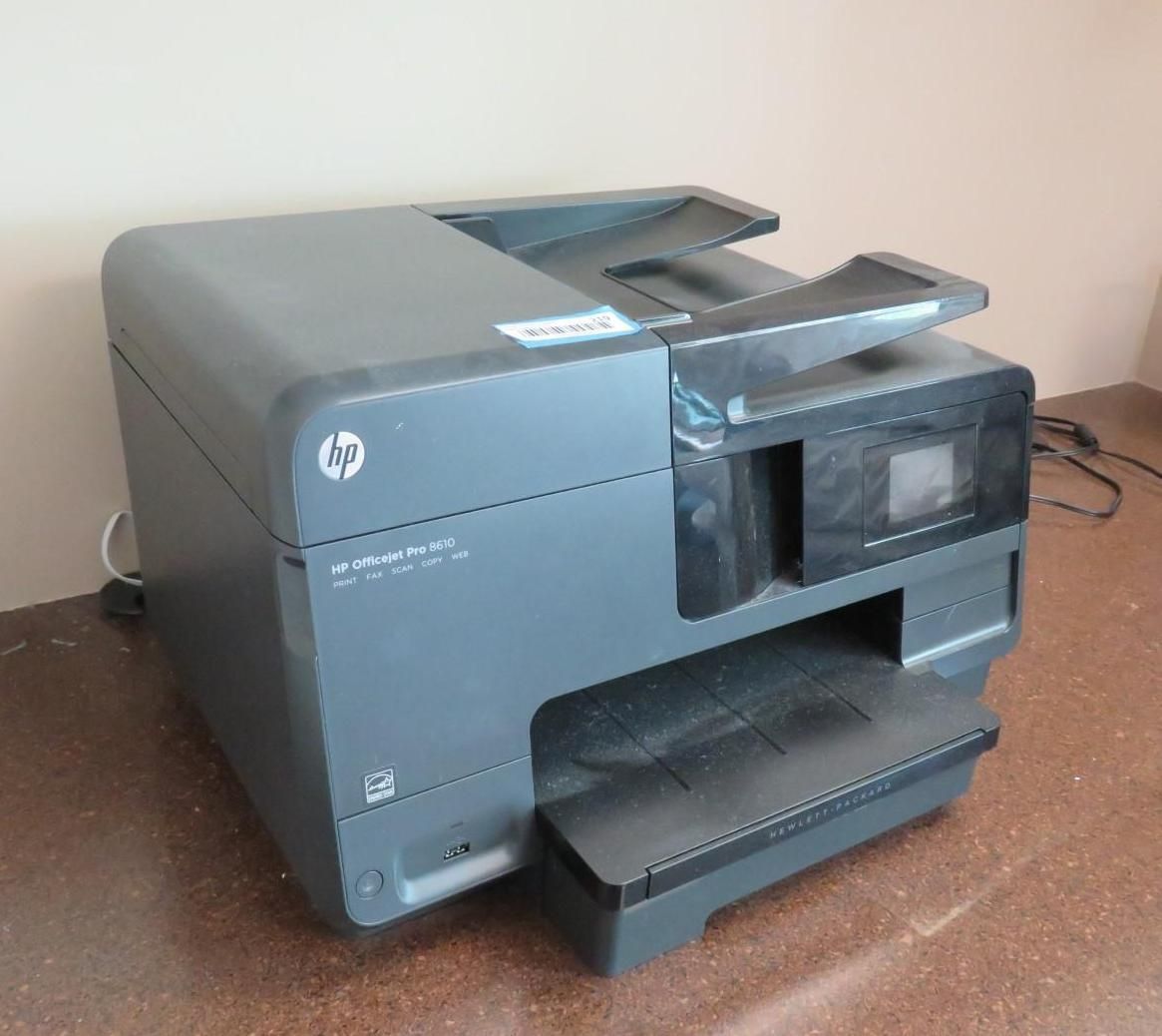 A dark gray HP OfficeJet Pro 8600 printer sitting on a brown surface.