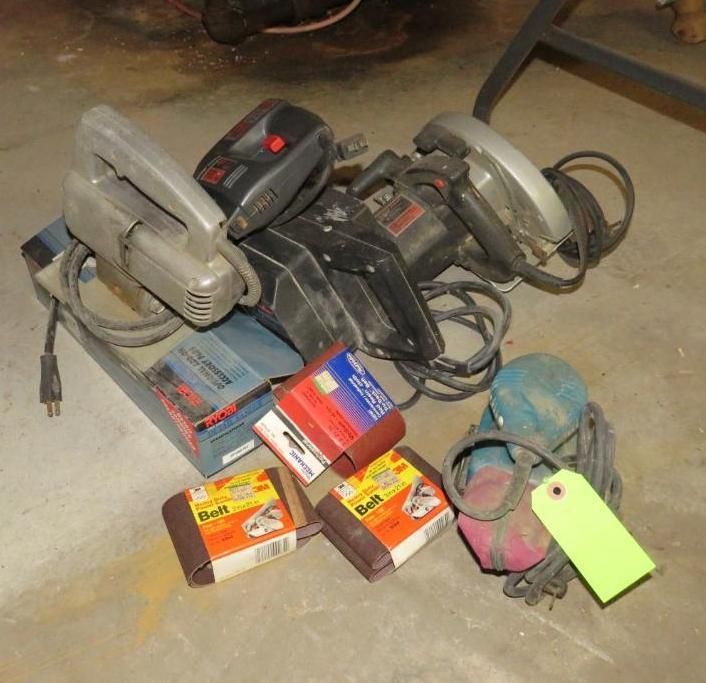 Power sanders and sandpaper on a concrete floor.