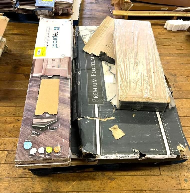 Boxes of flooring on a wooden pallet. One box is white and has