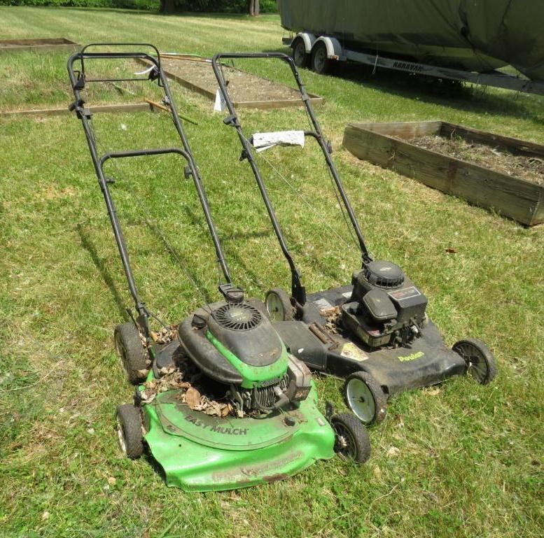 Two lawnmowers on a grassy lawn. One is green and black, the other black.