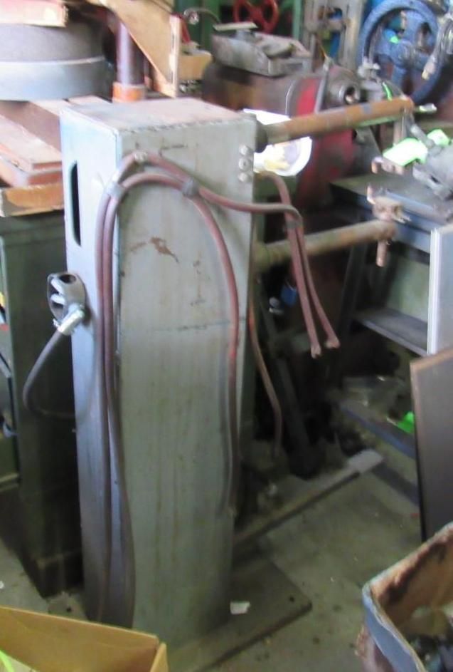 Metal industrial machine with tubes and wires, in a workshop setting.