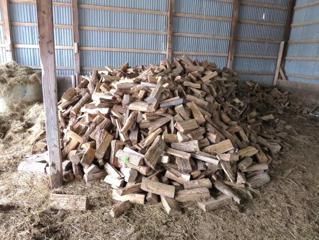 Pile of split firewood inside a wooden barn.