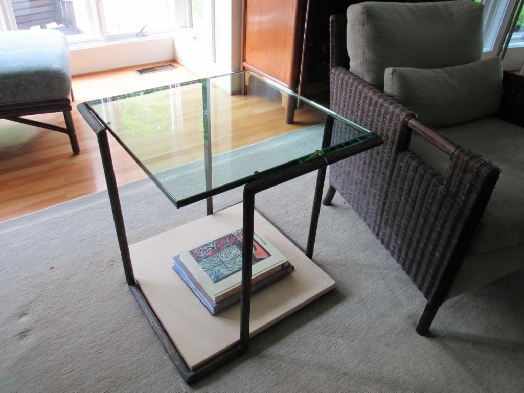 Glass-topped side table with a light-colored shelf holding a book.