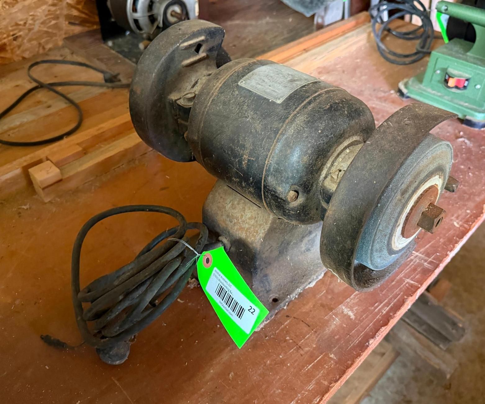 Black bench grinder on a wooden workbench with power cord