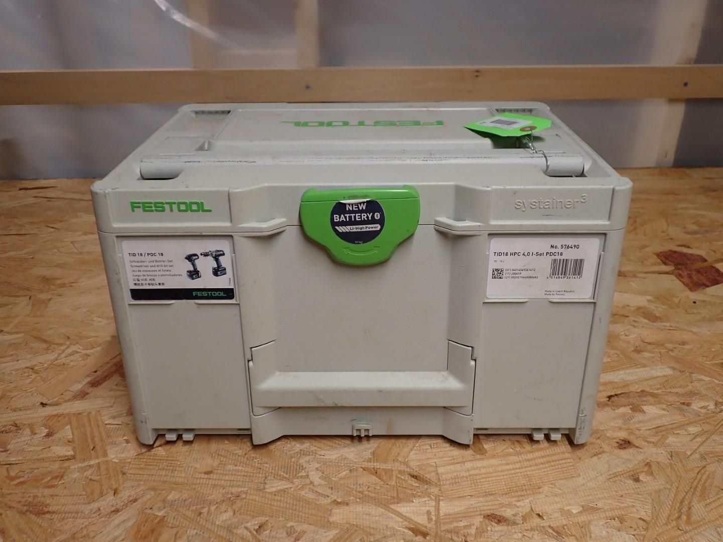 A closed Festool Systainer tool case, light gray with green accents, sitting on a wood surface.
