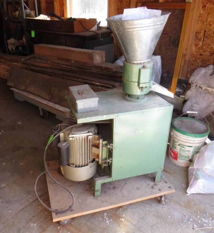 Green pellet mill machine with a silver hopper, wooden base, and a motor.