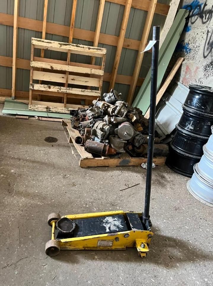 Yellow floor jack with a black handle in a storage area.