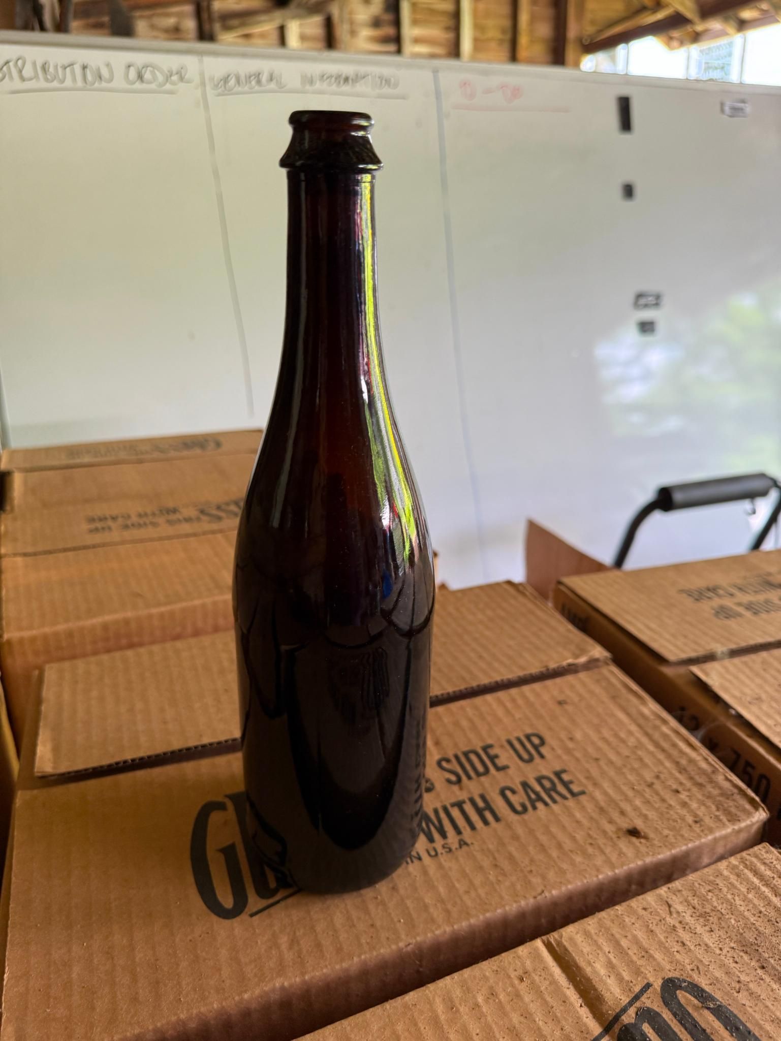 Dark glass bottle on cardboard boxes.