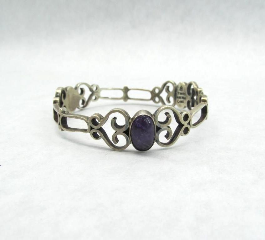 Silver bracelet with a purple oval stone set in a decorative frame.