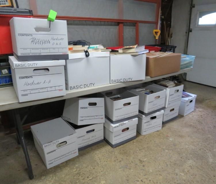 Boxes of various sizes stacked on a table and floor in a garage.
