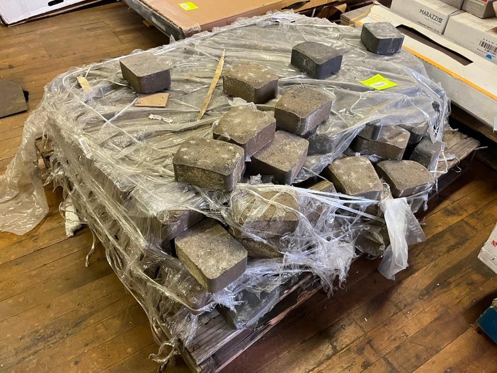 Pallet wrapped in plastic with square paving stones on top.