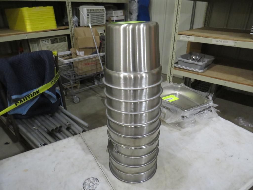 Stacked stainless steel bowls with white rings, in a warehouse setting.