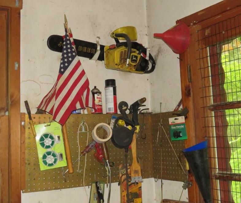 Workbench corner with chainsaw, American flag, tools, and funnels.