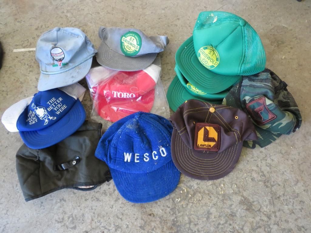 Pile of assorted caps in various colors and styles on a concrete surface.