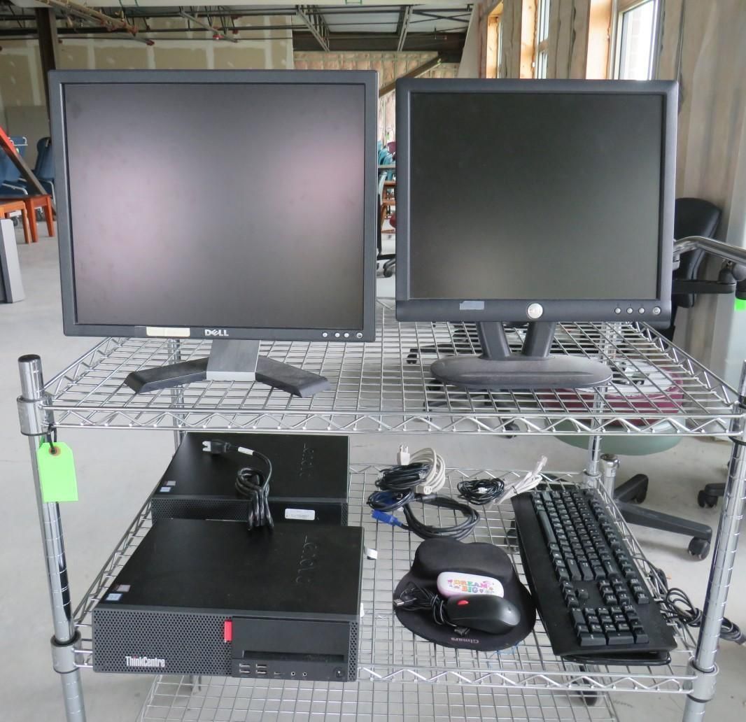 Two computer monitors, a computer tower, and peripherals on a wire rack.