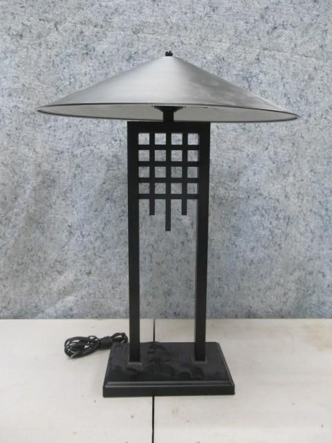 Black table lamp with square shade over a geometric frame on a black square base.