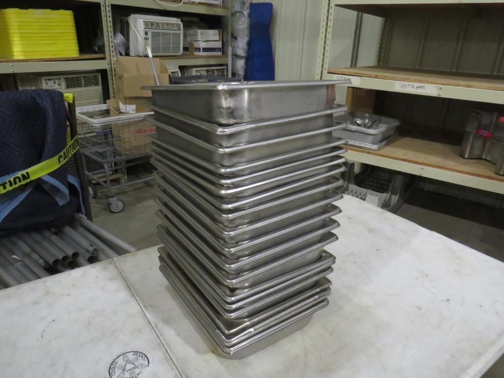 Stack of stainless steel food pans on a white surface.