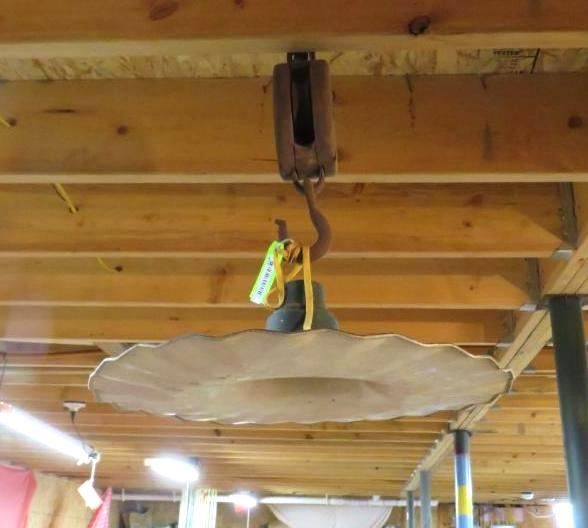 Ceiling light with a decorative, wide, scalloped shade, suspended from a wooden pulley.