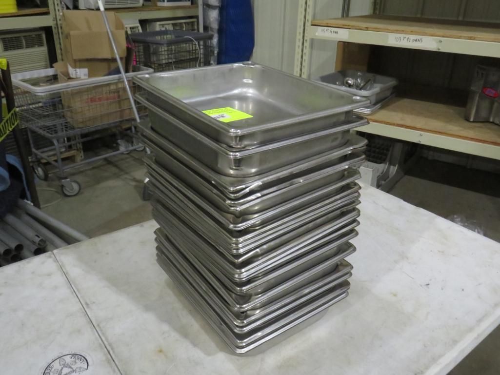 Stack of stainless steel food pans on a white table.