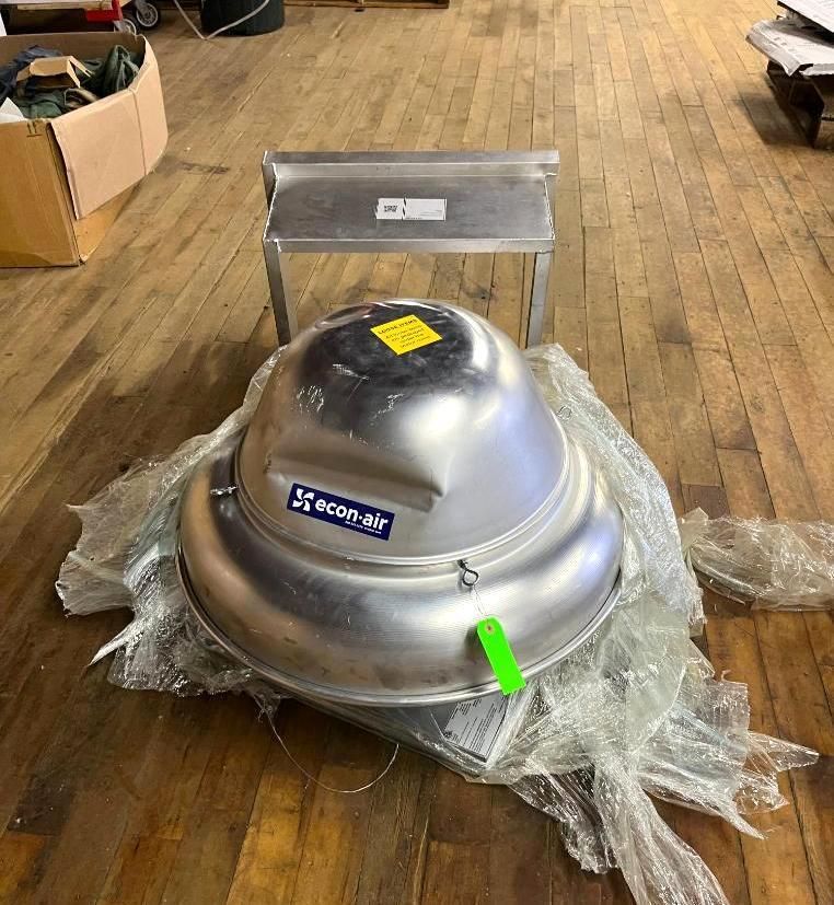 Large silver HVAC unit and a small stainless steel table on wooden floor.