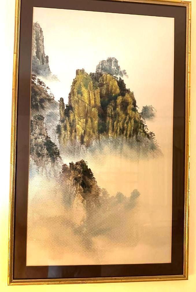 Landscape painting of misty mountains with a golden frame.