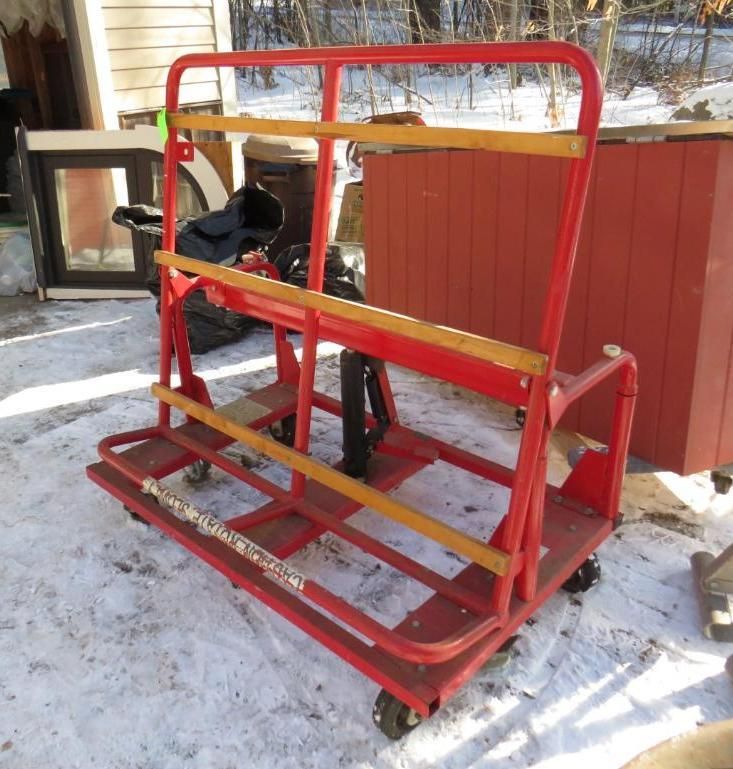 Red steel cart with wooden supports, on wheels, outside in the snow.