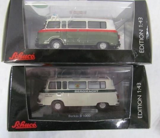 Two model cars in boxes: a green and red bus and a white