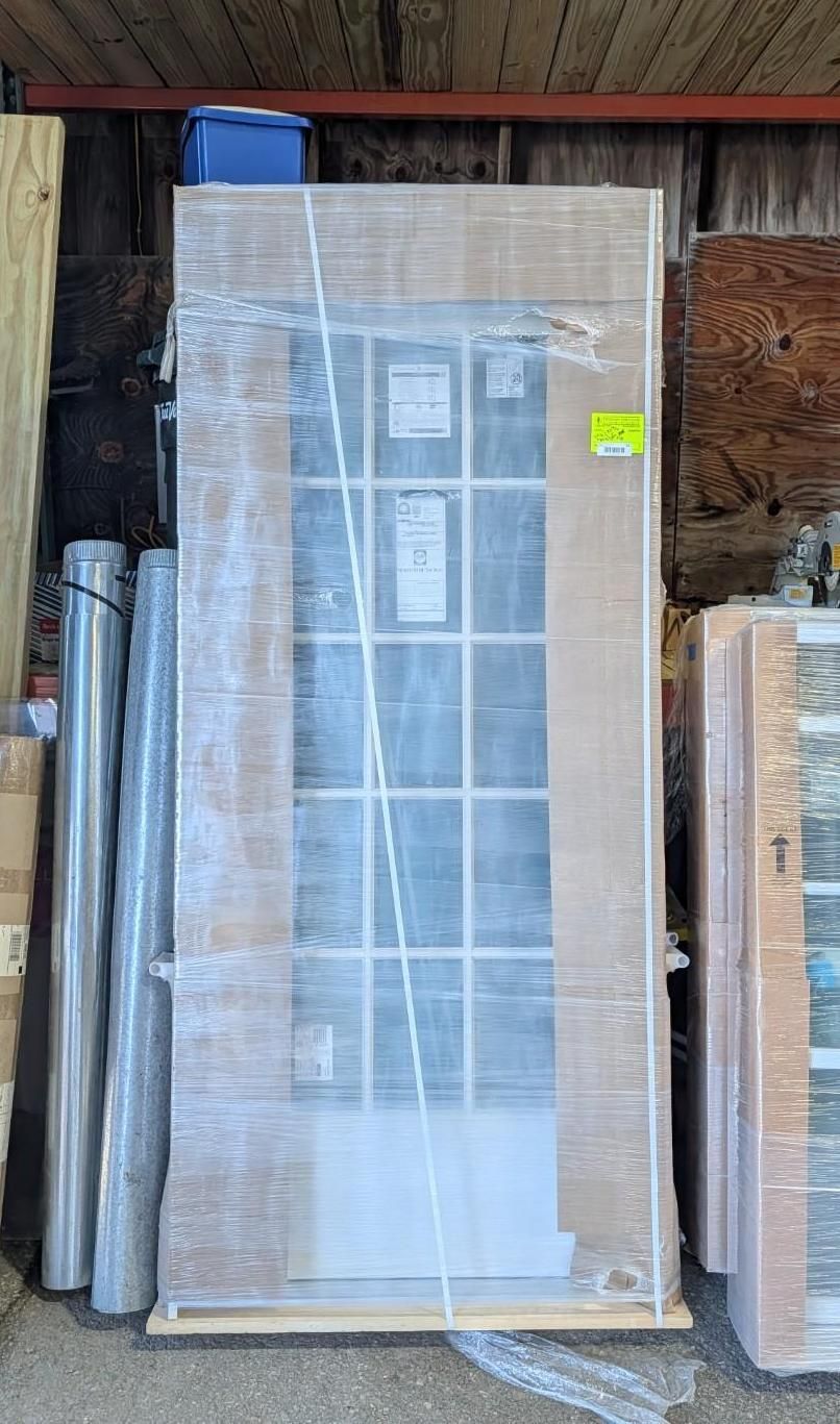 Wrapped white door or cabinet leaning in a storage area beside rolled materials