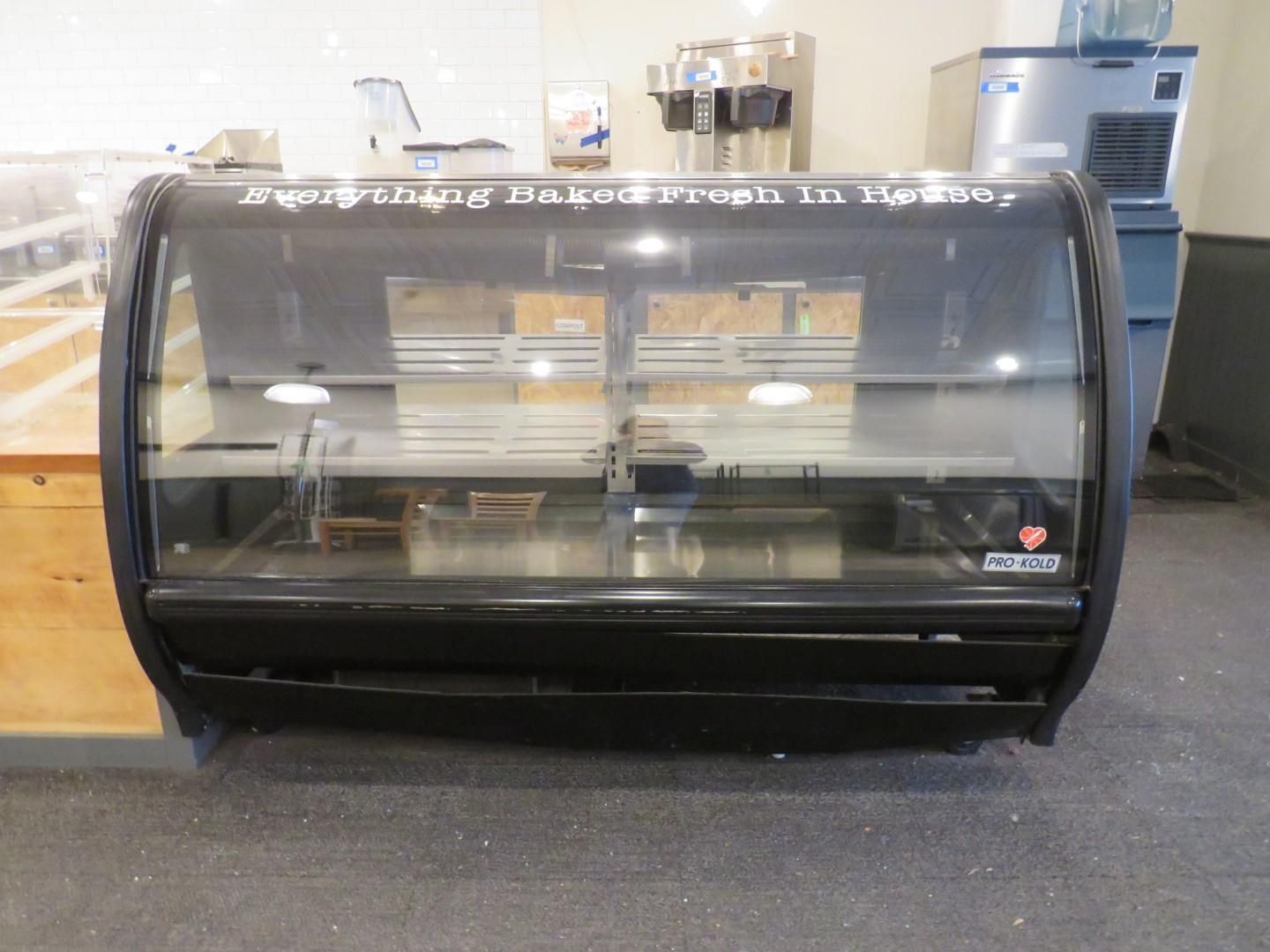 Black display case, shelves inside, possibly for bakery goods, against a light-colored wall.