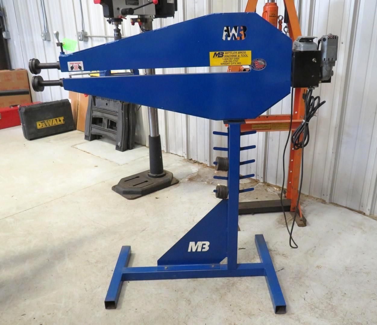 Blue metal fabrication machine on a blue metal stand in a workshop.