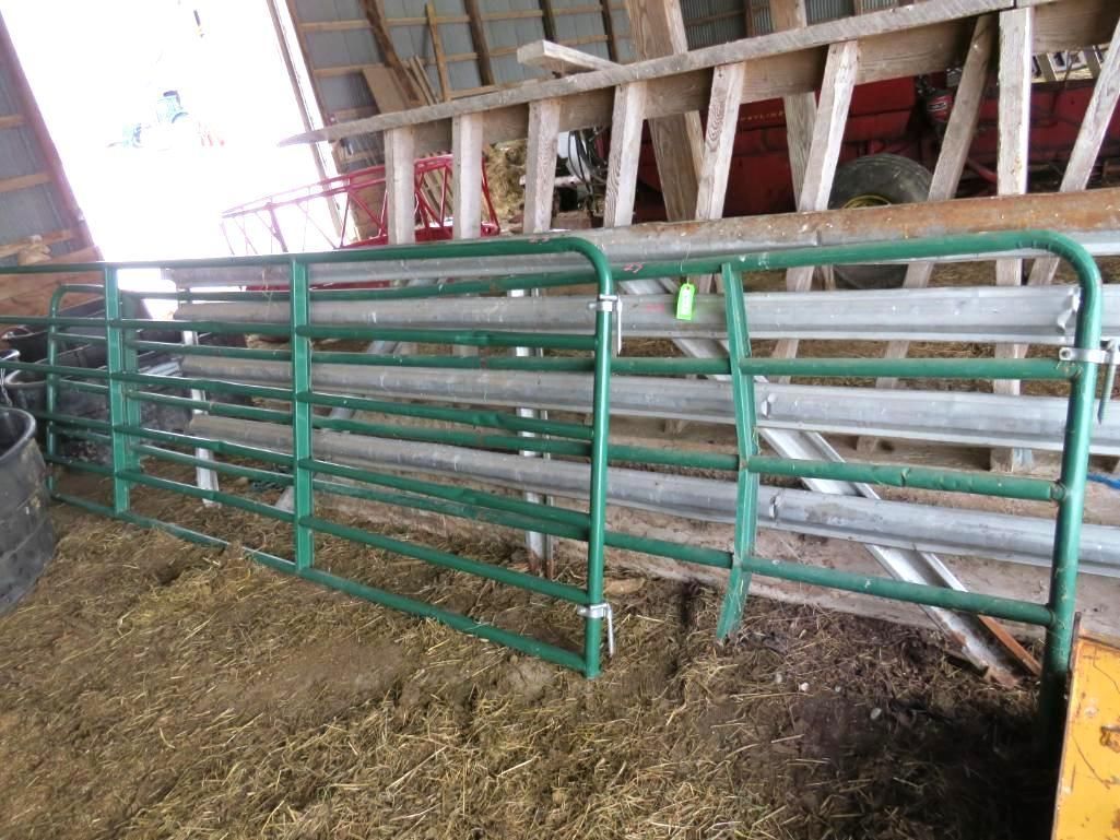 Green metal livestock gates inside a barn.