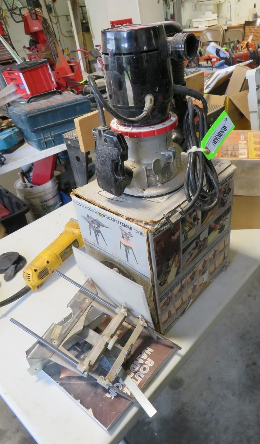 Router machine on a cardboard box, with a yellow heat gun and clamps on a table.