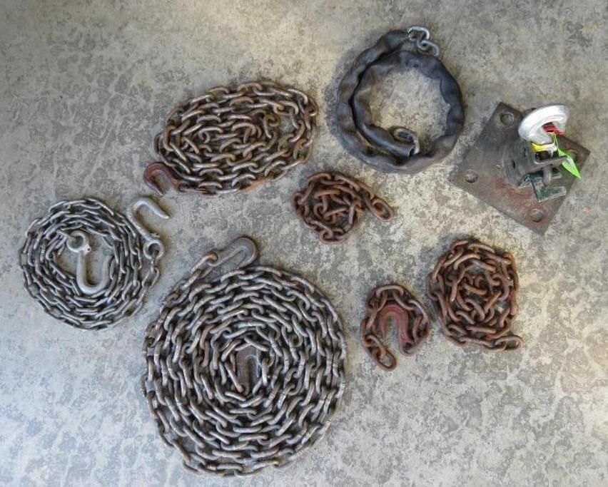 Assorted metal chains and a metal plate with electrical components on a textured surface.